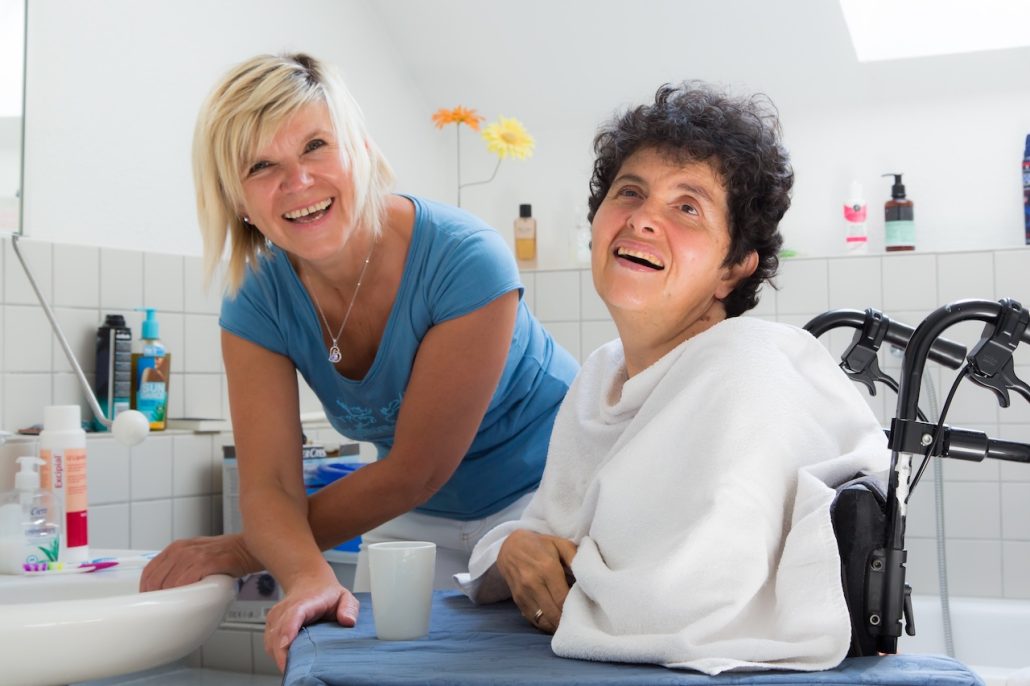 Frau wird unterstützt beim Zähne putzen und lacht